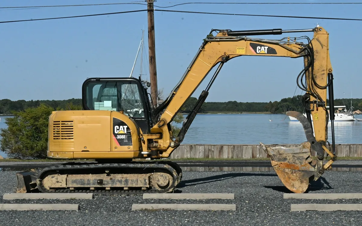 Used Caterpillar 308E2 CR mini excavator, side view in a gravel yard